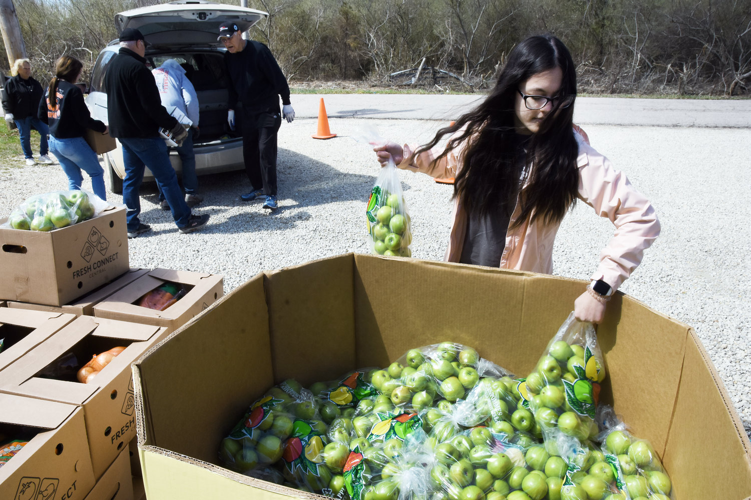 Mercedes Baguio selects a bag of apples to distribute Thursday at the Helping Hands Outreach Center’s Mobile Market.