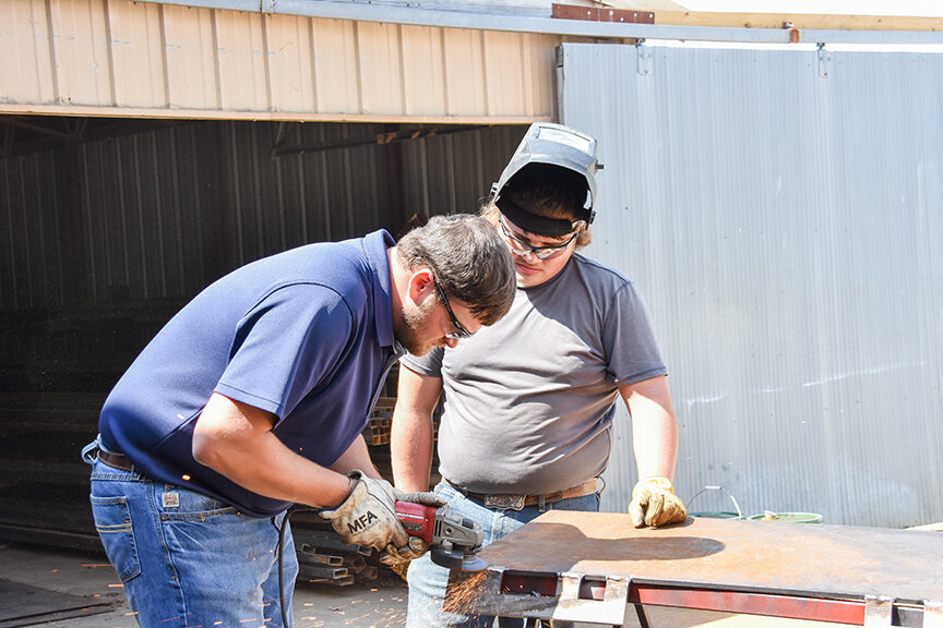 First-year agriculture teacher Trent Stockton helps a sixth-hour student prepare to weld on a skid steer plate. Stockton took over for former ag teacher Chris Mertz who retired in May.